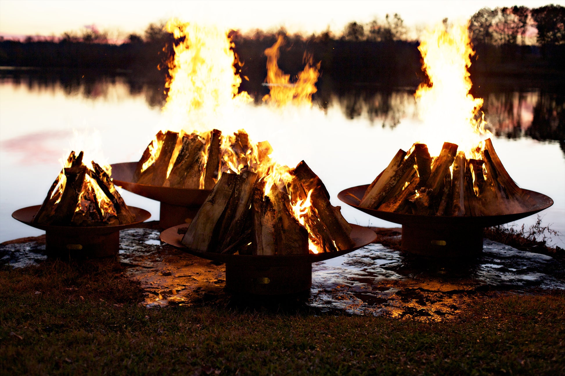 Luxurious Asia fire pit collection burning with logs along waters edge. 