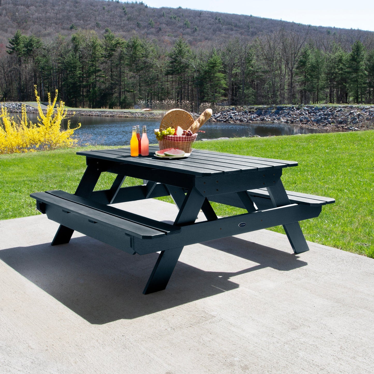 Ember & Oasis presents the Homestead 6' Picnic Table in a beautiful outdoor setting next to a pond with trees and a mountain background. This is manufactured 100% in the USA from high-quality poly lumber and comes with a limited 15 year residential and 7 year commercial warranty! 