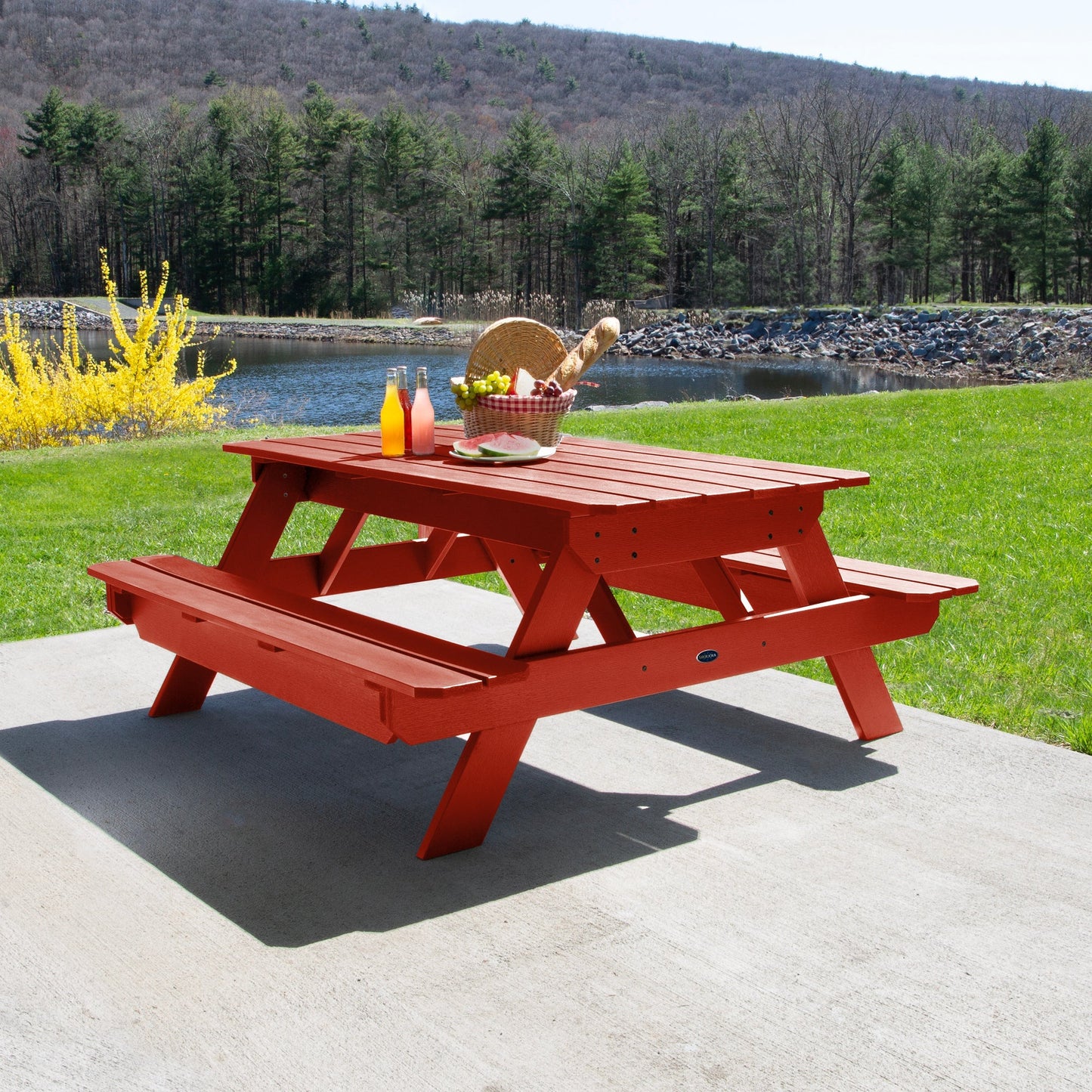 Ember & Oasis presents the Homestead 6' Picnic Table in a beautiful outdoor setting next to a pond with trees and a mountain background. This is manufactured 100% in the USA from high-quality poly lumber and comes with a limited 15 year residential and 7 year commercial warranty! 