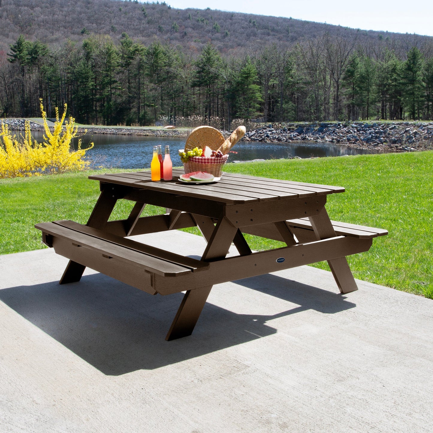 Ember & Oasis presents the Homestead 6' Picnic Table in a beautiful outdoor setting next to a pond with trees and a mountain background. This is manufactured 100% in the USA from high-quality poly lumber and comes with a limited 15 year residential and 7 year commercial warranty! 